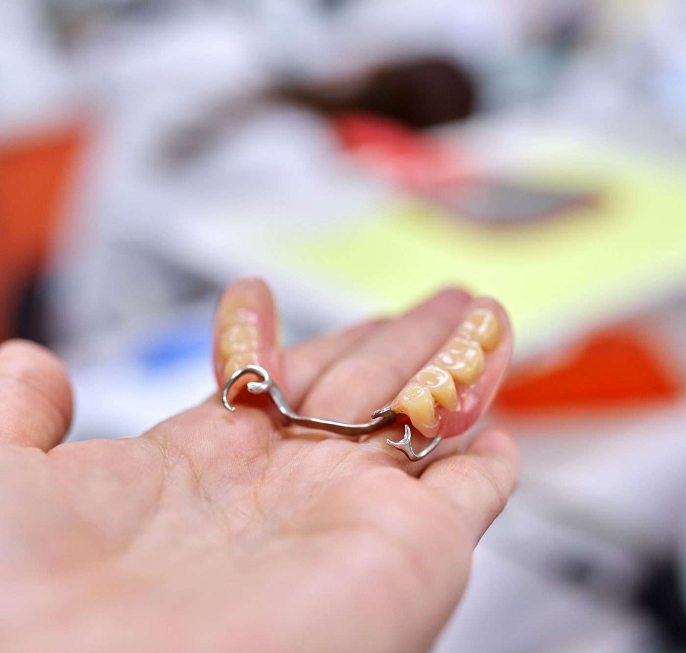 Dental implant model dental bridge in hand, dentist office background