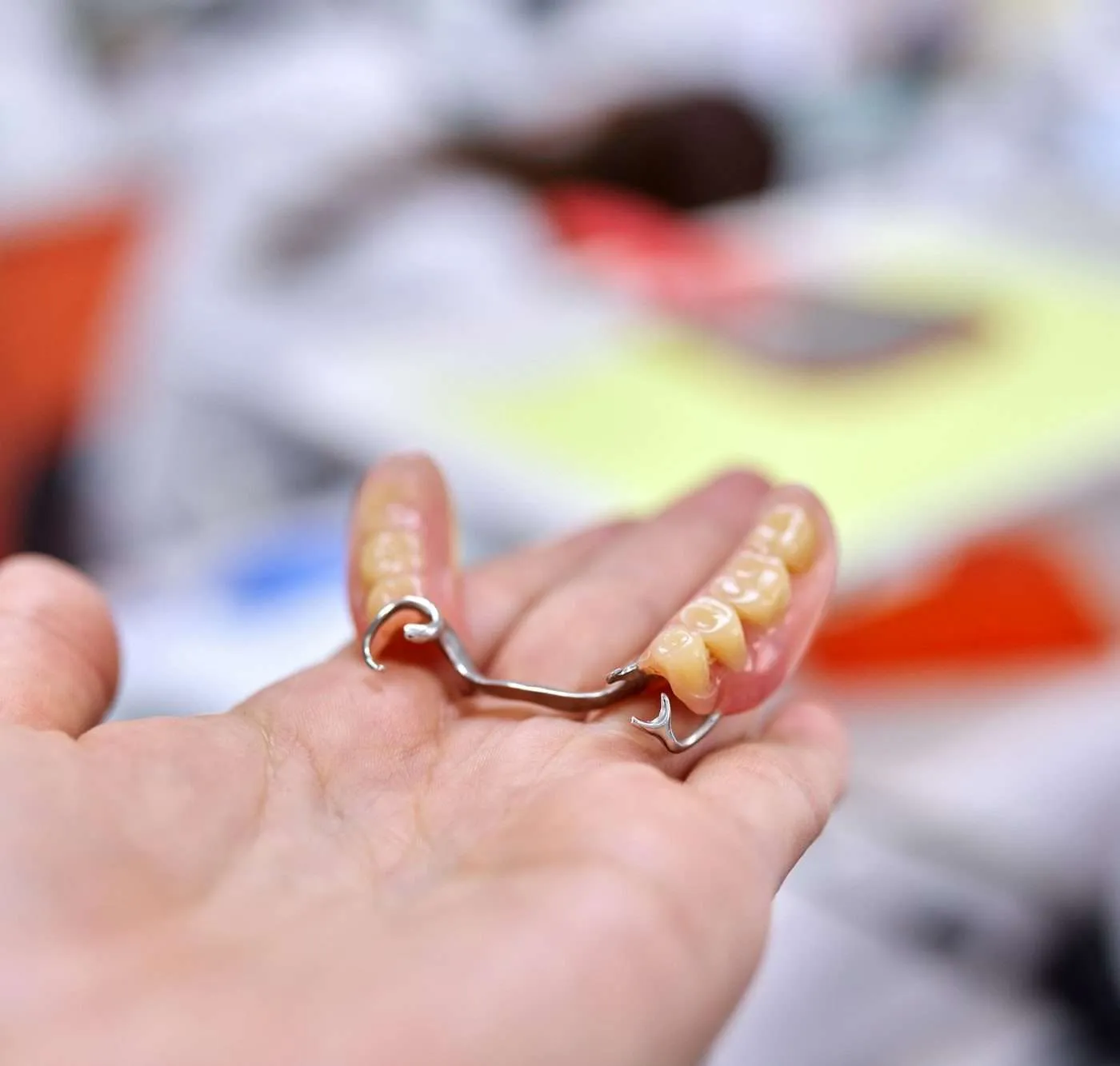 Dental implant model dental bridge in hand, dentist office background