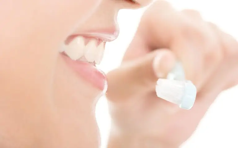 Close-up of a person smiling while brushing their teeth with a toothbrush, showing white teeth and part of their lips and chin—perfect results enhanced by a Take Home Whitening System.